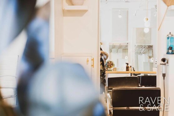 Mirror reflection of stylist doing hair at Raven & Sage Salon San Diego
