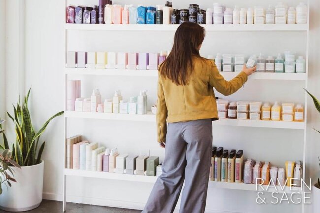 Woman selecting a product on a wall at Raven & Sage Salon San Diego